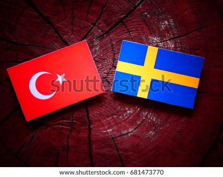 Turkish flag with Swedish flag on a tree stump isolated