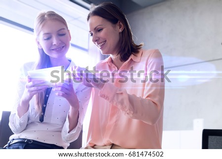Smiling young businesswomen using mobile phone in office