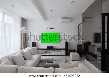 Interior of a stylish light living room in a modern style, TV with a green screen
