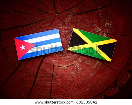 Cuban flag with Jamaican flag on a tree stump isolated