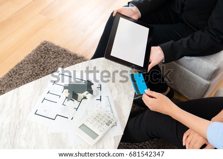 high angle view photo of saleswoman using mobile digital tablet pad showing deal document and buyer using credit card paying money