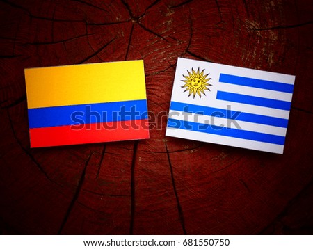 Colombian flag with Uruguayan flag on a tree stump isolated
