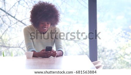 Handsome young african american woman drinking coffee and using a mobile phone at  home