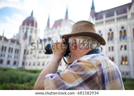 Senior pensioner photographing Parliament Building Budapest, Hungary