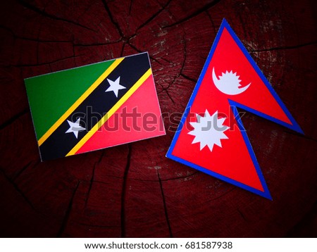 Saint Kitts and Nevis flag with Nepali flag on a tree stump isolated