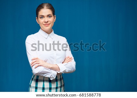 Smiling young woman wearing white shirt with crossed arms standing against blue background