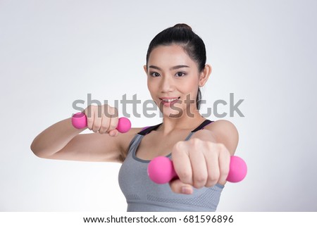 Young beautiful asian sporting woman training with dumbbell. Pretty athletic girl making physical exercise against white background. Healthy lifestyle concept.