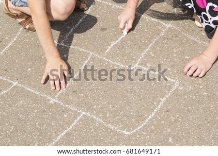 Children playing outside and drawing on the asphalt. 