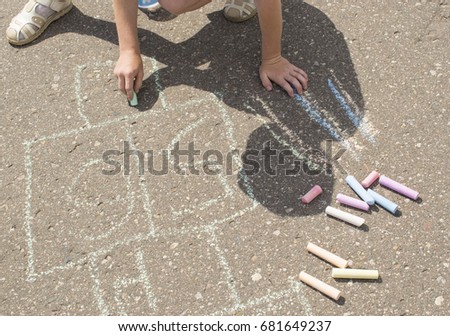 Child playing outside and drawing on the asphalt. 