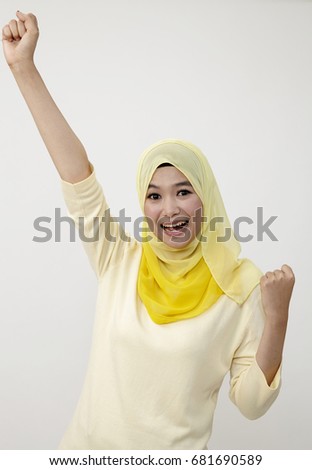 Studio shot of young woman celebrating with arm raised Stock Photography