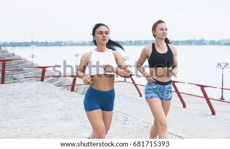 Two sportive pretty women running outdoors at morning - Female friends training in the morning