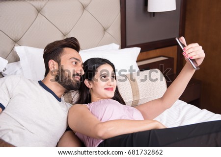 Young couple taking pictures on bed