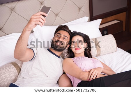 Young couple taking pictures on bed