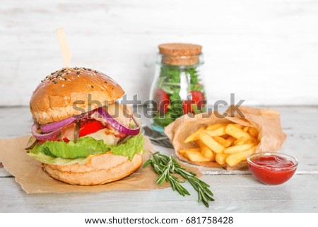 Composition with tasty homemade burger, french fries and bowl of ketchup on wooden table
