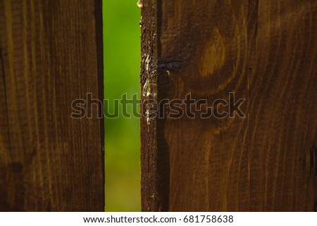A drop of tar flows on the board. Wooden fence. Background.