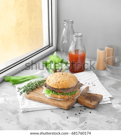 Composition with delicious homemade burger, tomato juice and vegetables on windowsill. Concept of food photography