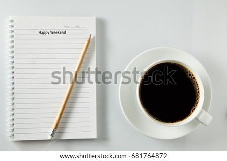 White cup of coffee morning on wooden table with notebook,soft focus photo, happy weekend concept