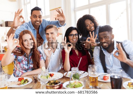 eating, food and people concept - group of happy international friends showing ok hand sign at restaurant table