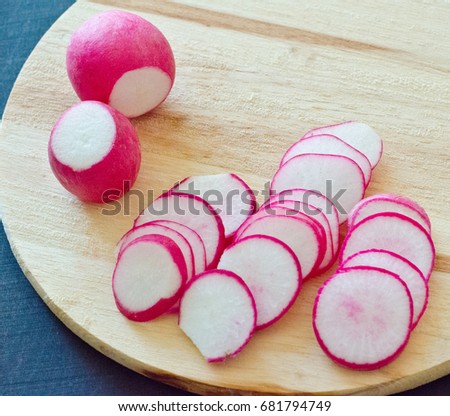 Round radishes cut slices on wooden Board black background