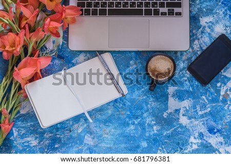 Workplace concept. Views of the blue Desk with laptop, telephone, white pad and pencil. Black Cup of coffee. Flat lay. A place for your inscription. Background for site design, landing page or blog. 