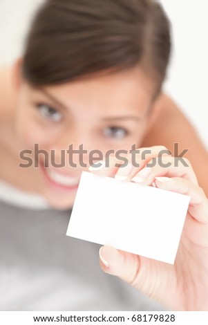 Person showing business card. Casual woman smiling holding the card. Shallow depth of field, focus on paper with empty copy space.