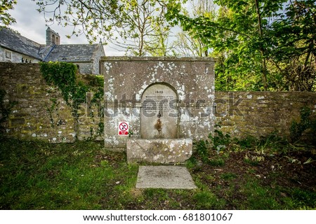funny contrast medieval church water fountain with bible quote and modern do not drink sign at tyneham ghost village dorset