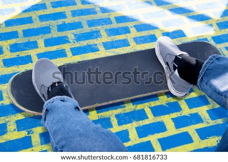 Stylish teenager boy wearing a checkered shirt and jeans on skateboard over colorful background