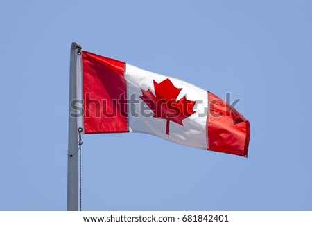 Canadian flag on flag pole blowing in wind, waving with upper right corner curled, patriotism and country symbol
