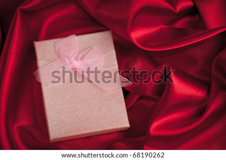 gift with decorative pink ribbon on red silk background