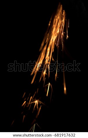 Fire sparks on a black background during metal cutting, hot burning element in flame