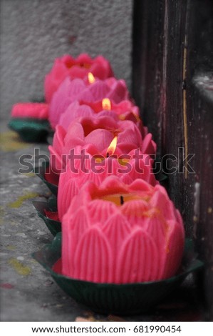 Perspective image of a row of pink lotus flower candles in a Chinese temple in Asia