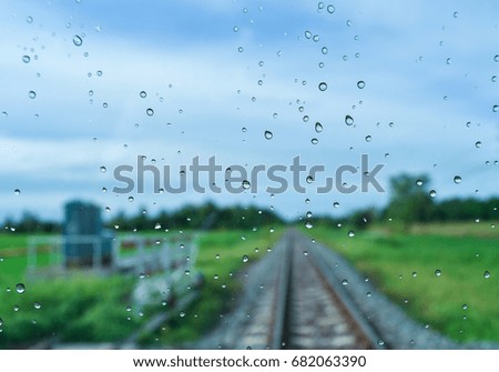 Green field after rain with water drops behind the window middle the railroad in the countryside of Thailand.