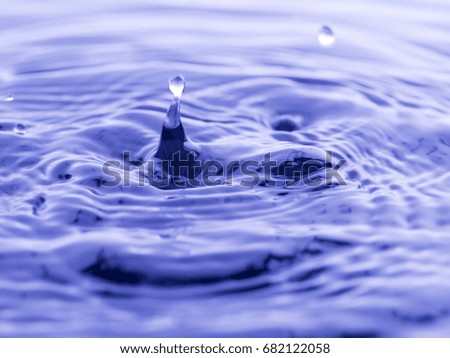 Water drop falling into blue water abstract background