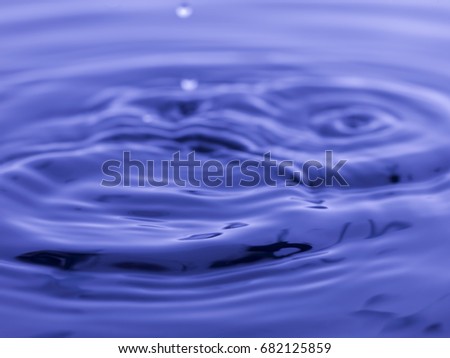 Water drop falling into blue water abstract background 