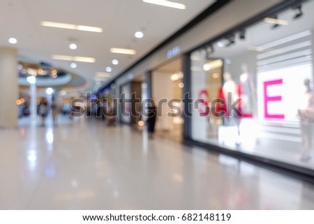 Blurred image of shopping mall and people walking for background usage, Sale banner  in shop window.