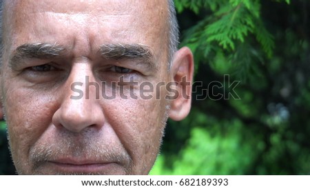 portrait of adult man with stubble,against the background of green needles.