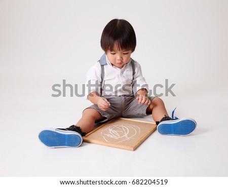 chinese boy holding white chalk writting on black board