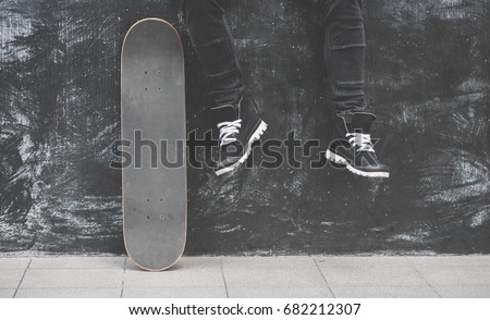 Boy skater is sitting on the wall with a skateboard