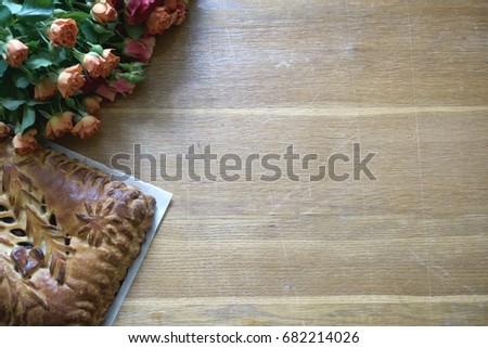 Fresh made yeast cake on the parchment and roses flowers, top view with copy space, full frame pic