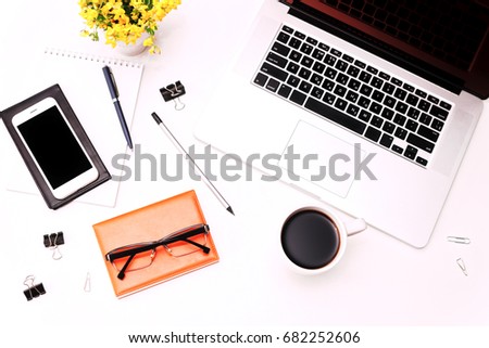 Workspace with laptop keyboard, coffee, mobile phone, glasses and flowers on the white background. Flat lay, top view