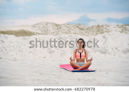 Woman practices yoga and meditates in the lotus position on the beach