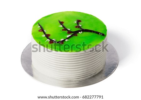 French smooth cake covered with green glaze isolated on white. White modern European dessert with picture of sakura branch.
