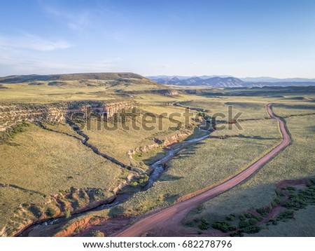 northern Colorado foothills aerial view - dirt road and whitewater stream n summer scenery
