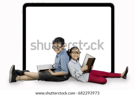 Image of two elementary students is learning with books and sitting near a blank billboard in the studio