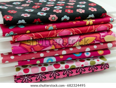 Stack of small bolts of cotton fabric in shades of red and pink Royalty-Free Stock Photo #682324495