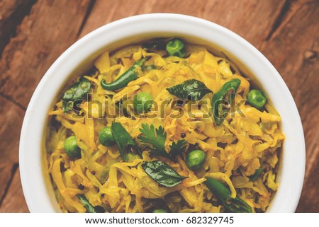 Patta Gobi Sabji OR Cabbage sabzi with green peas and curry leaves, served in a bowl over moody background, selective focus
