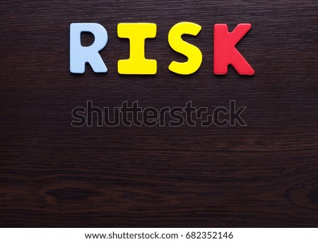 Risk colorful letters on dark brown background.