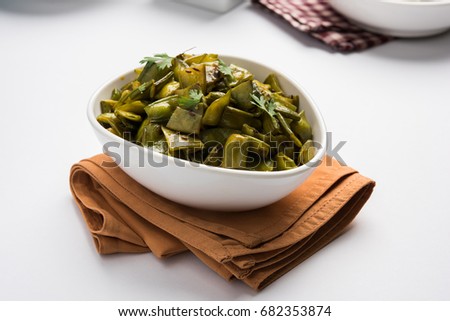 A Masala or fried vegetable dish consisting of flat green beans, onions, and curry spices, served in swuare bowl, selective focus