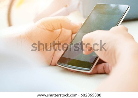 Close-up of female hands using smart phone with flare light background. Searching Internet ,Social Networking Concept