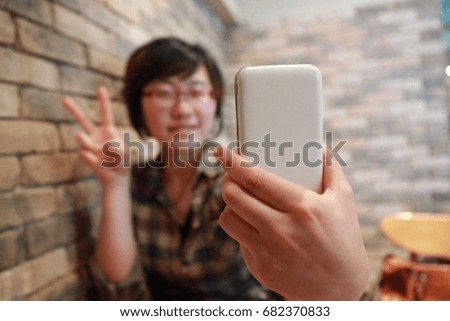 An Asian woman taking a cellphone self-shot.